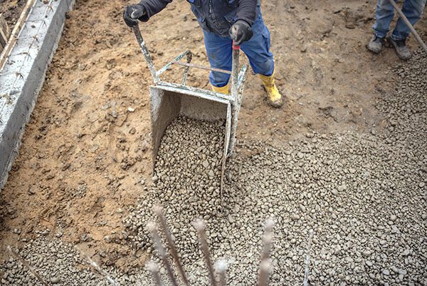 Construction worker carrying and unloading gravel and stones wit
